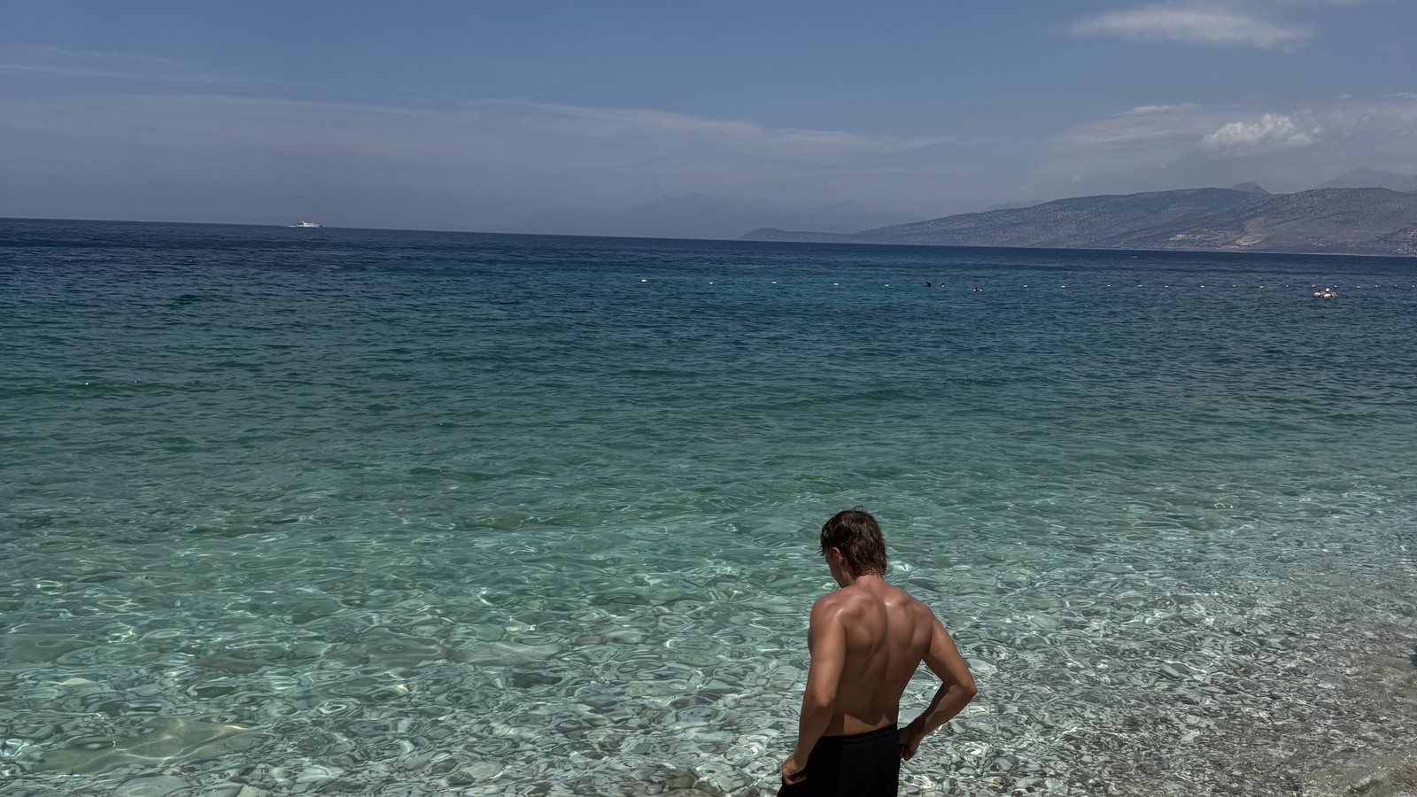 Daniel standing in clear shallow water at Pulebardha Beach near Sarande, Albania