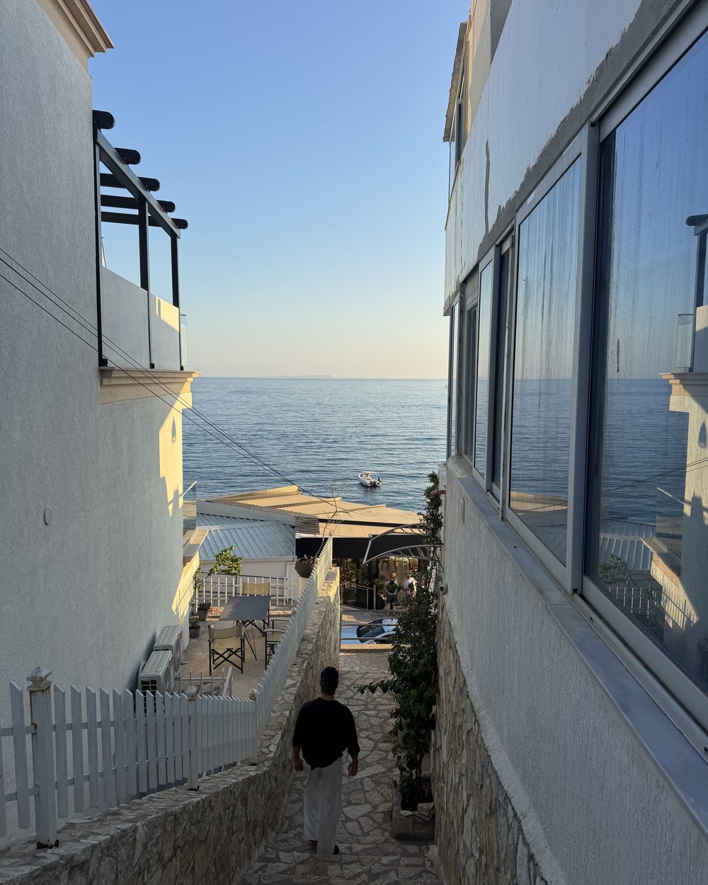 Narrow lane between white buildings opening onto the sea at Himarë, Albania