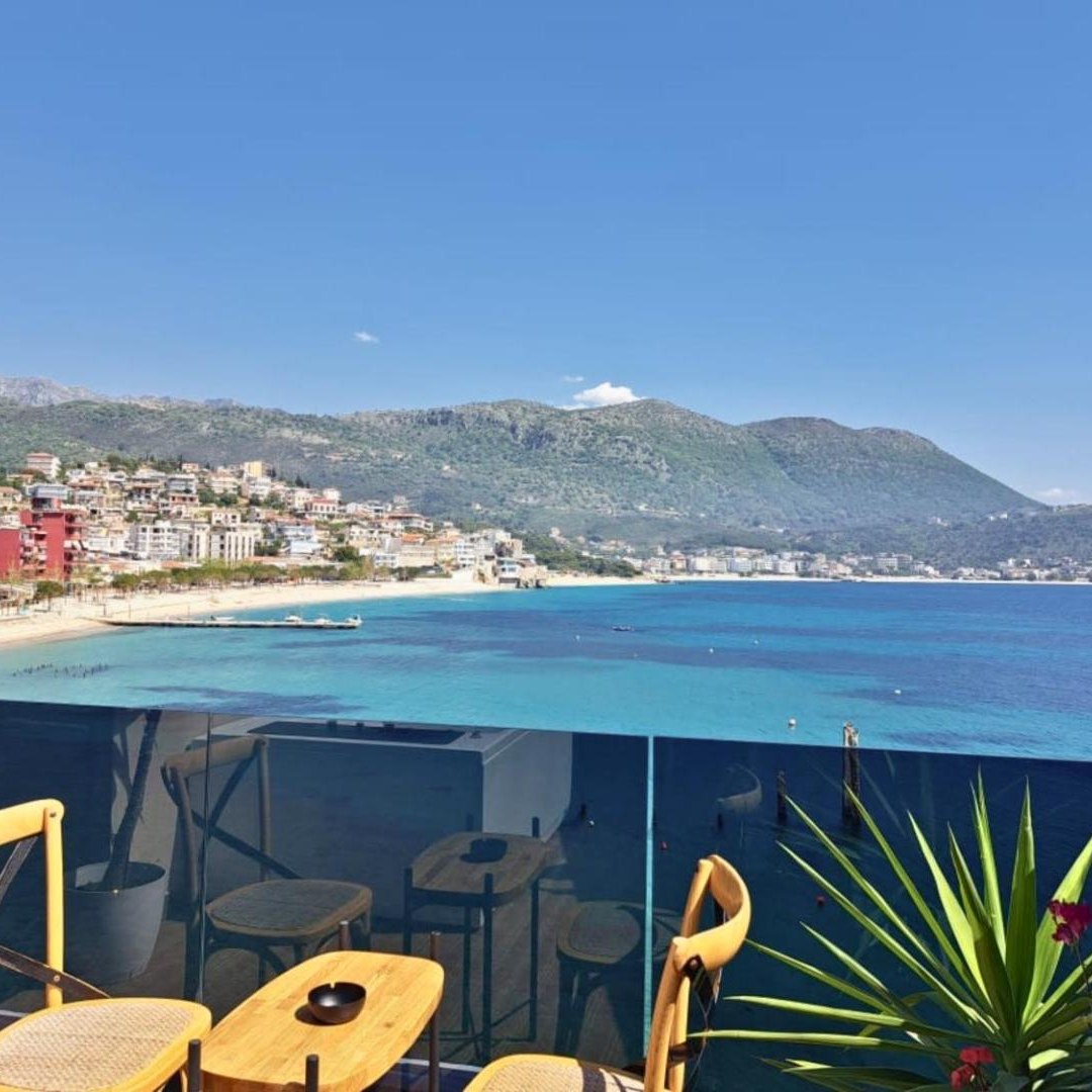 Balcony table and chairs looking along the beach and mountains at Rea Boutique Hotel in Himarë