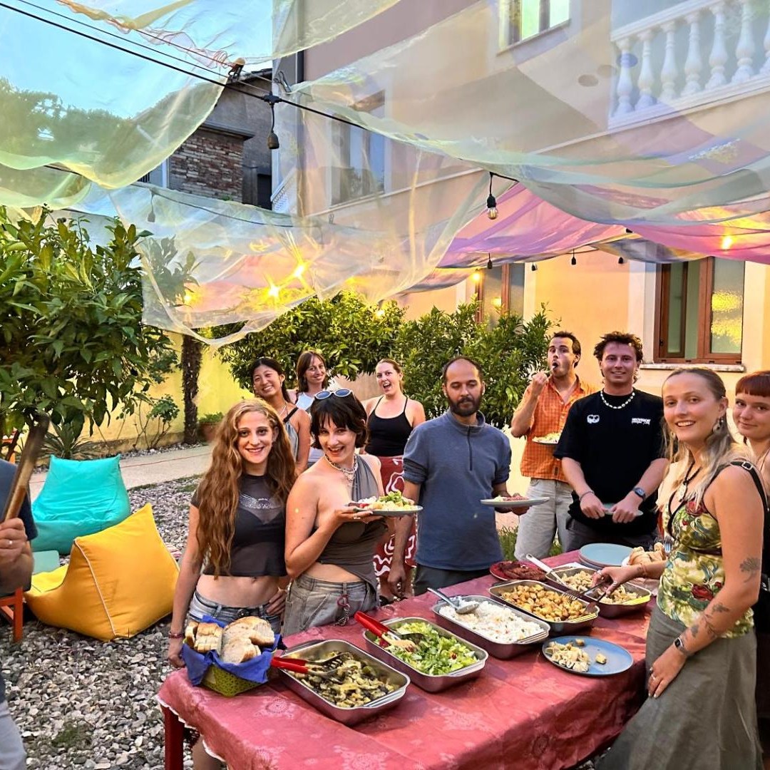 Guests serving themselves from a long table of shared food in the garden at Tias Hostel in Shkodër