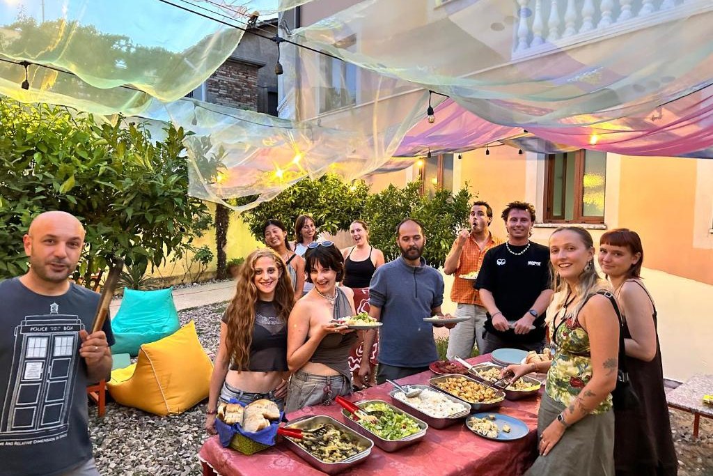 Guests serving themselves from a long table of shared food in the garden at Tias Hostel in Shkodër