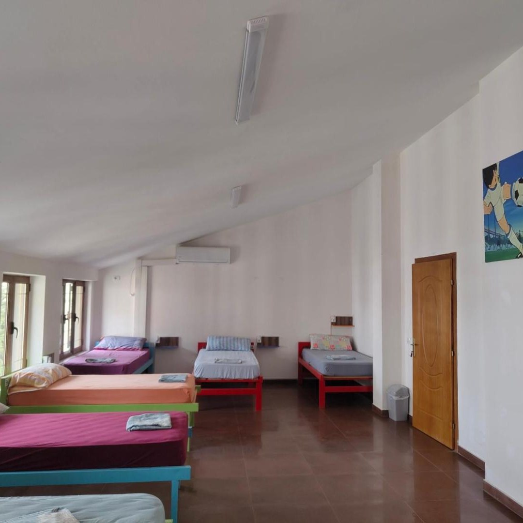 Bright room with several single beds under a sloped ceiling at Tias Hostel in Shkodër
