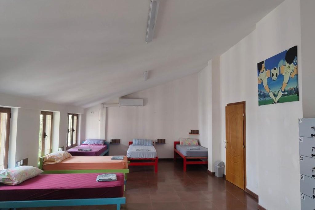 Bright room with several single beds under a sloped ceiling at Tias Hostel in Shkodër
