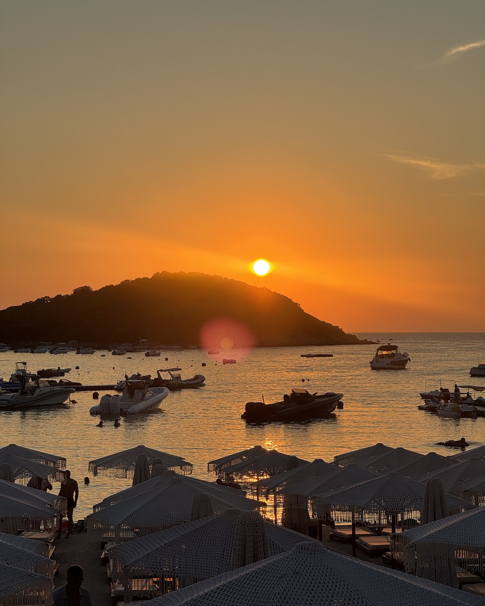 Sunset over the water and beach umbrellas seen from Greg Restaurant in Ksamil, Albania