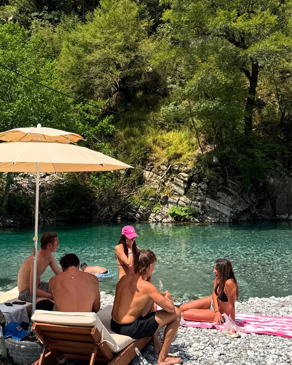 Sunloungers and swimmers on the pebble bank of the Shala River, Albania