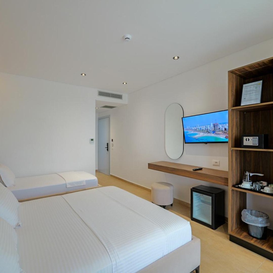 Bright double room with a television and shelving at Sunlight Hotel in Ksamil, Albania