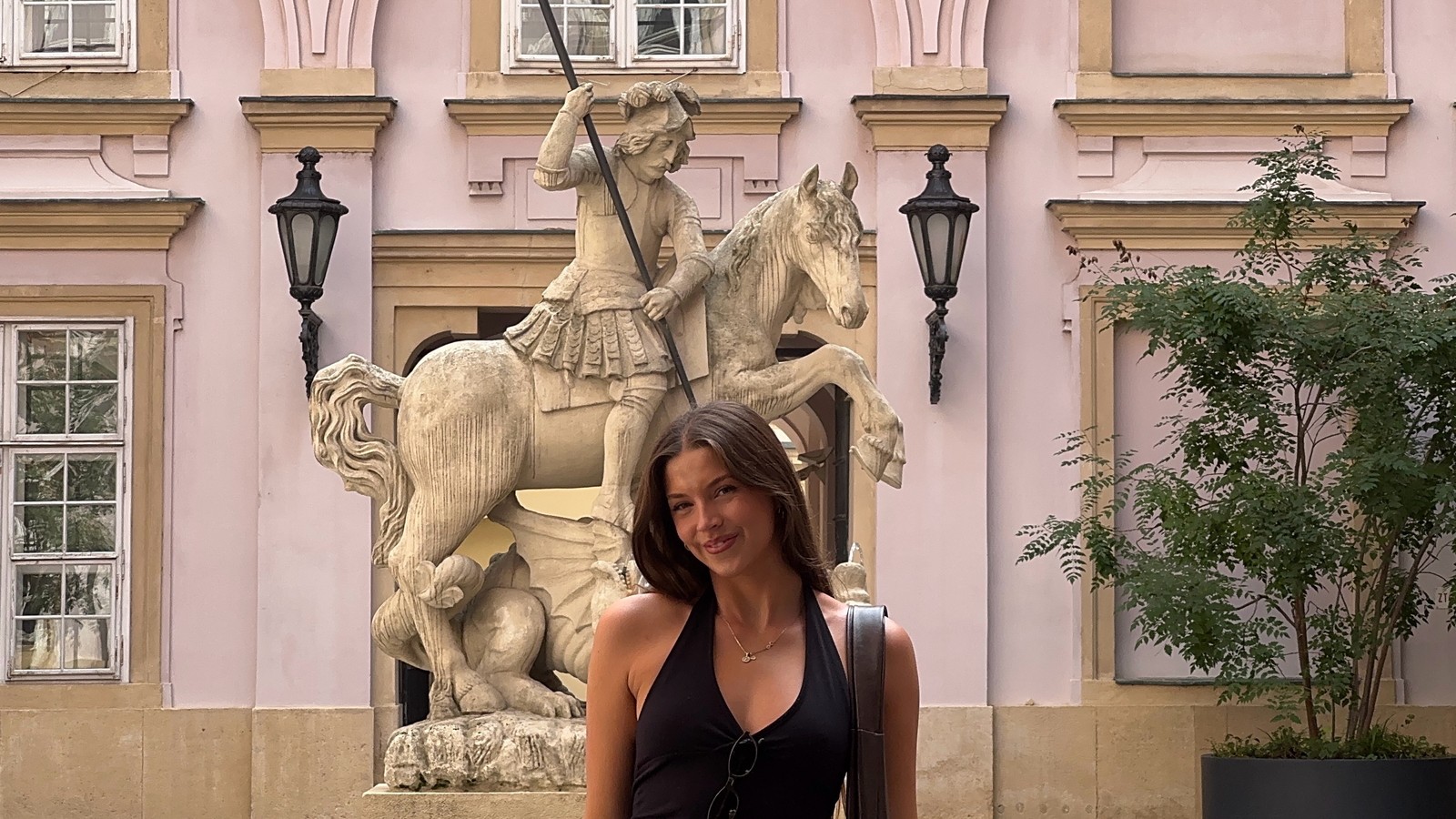 Woman standing by the St George fountain in front of the pink Primate's Palace in Bratislava