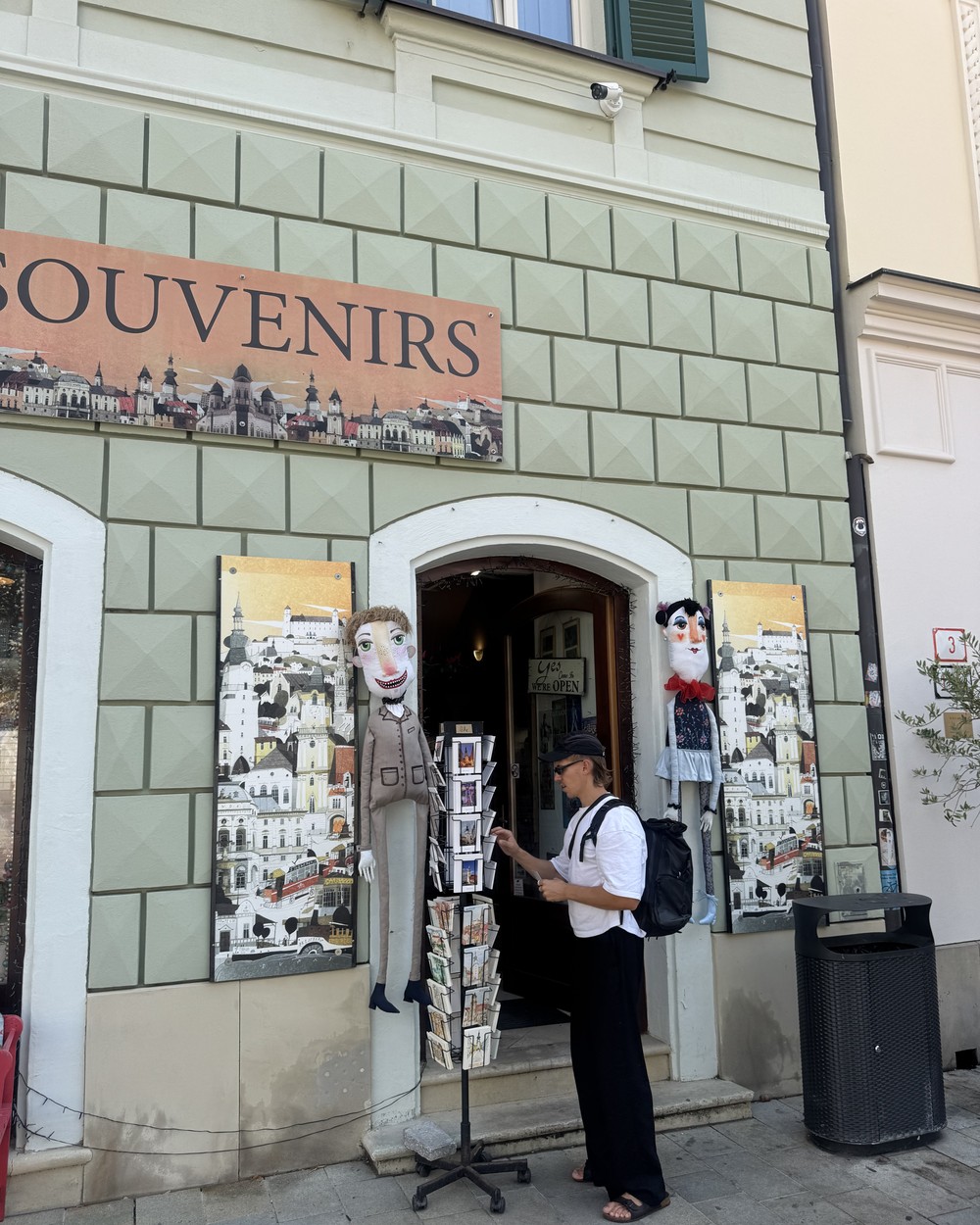 Man browsing a postcard stand outside a souvenir shop in Bratislava old town
