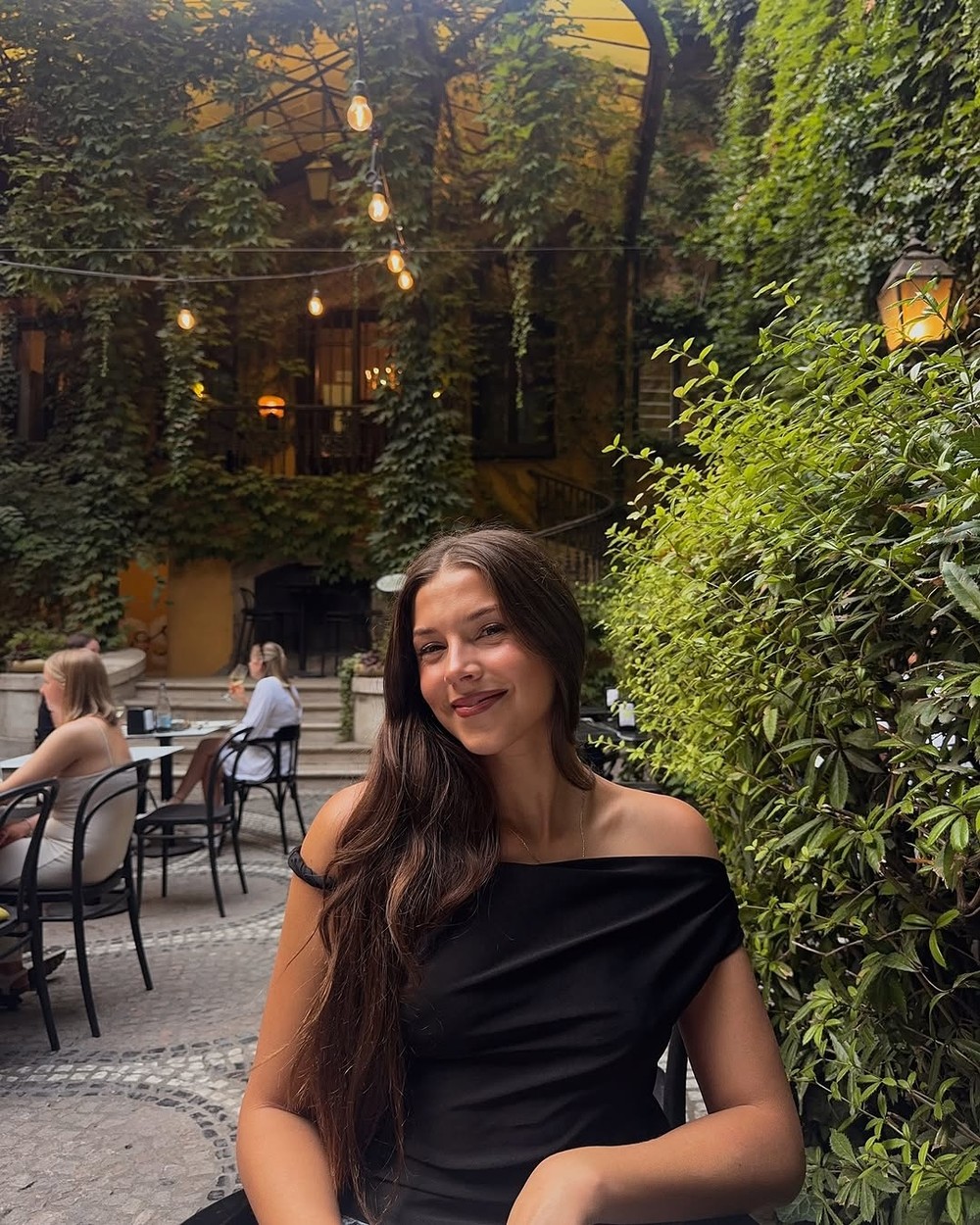 Woman sitting at a table in the leafy courtyard of Arquitecto Pitpit restaurant in Budapest