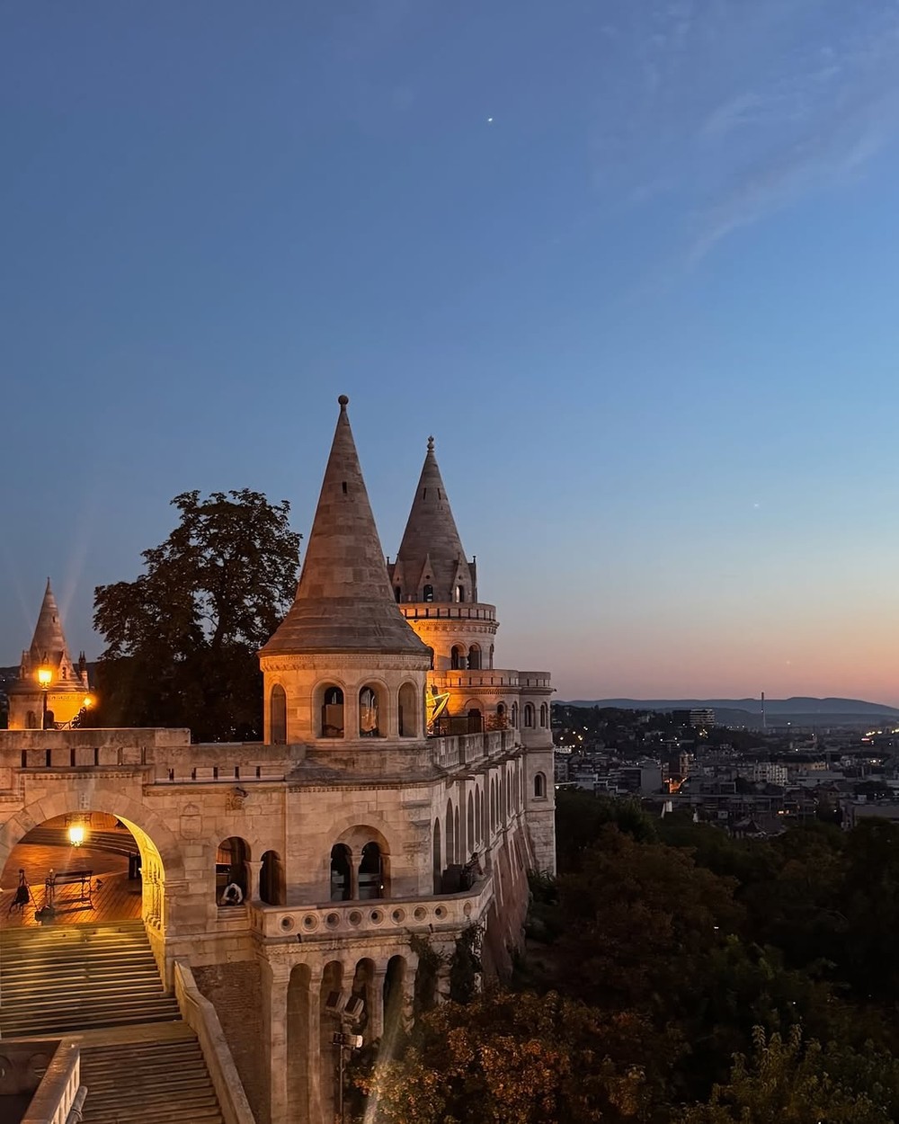 The turrets of Fisherman's Bastion lit up at dusk above Budapest