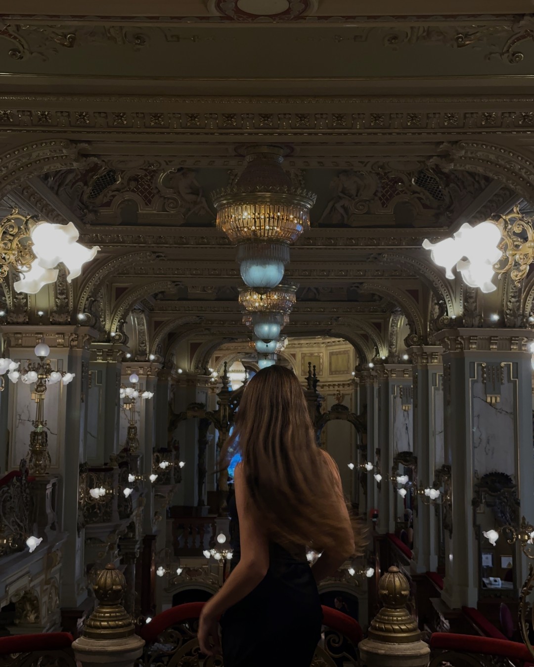 Woman standing in the gilded interior of New York Cafe in Budapest