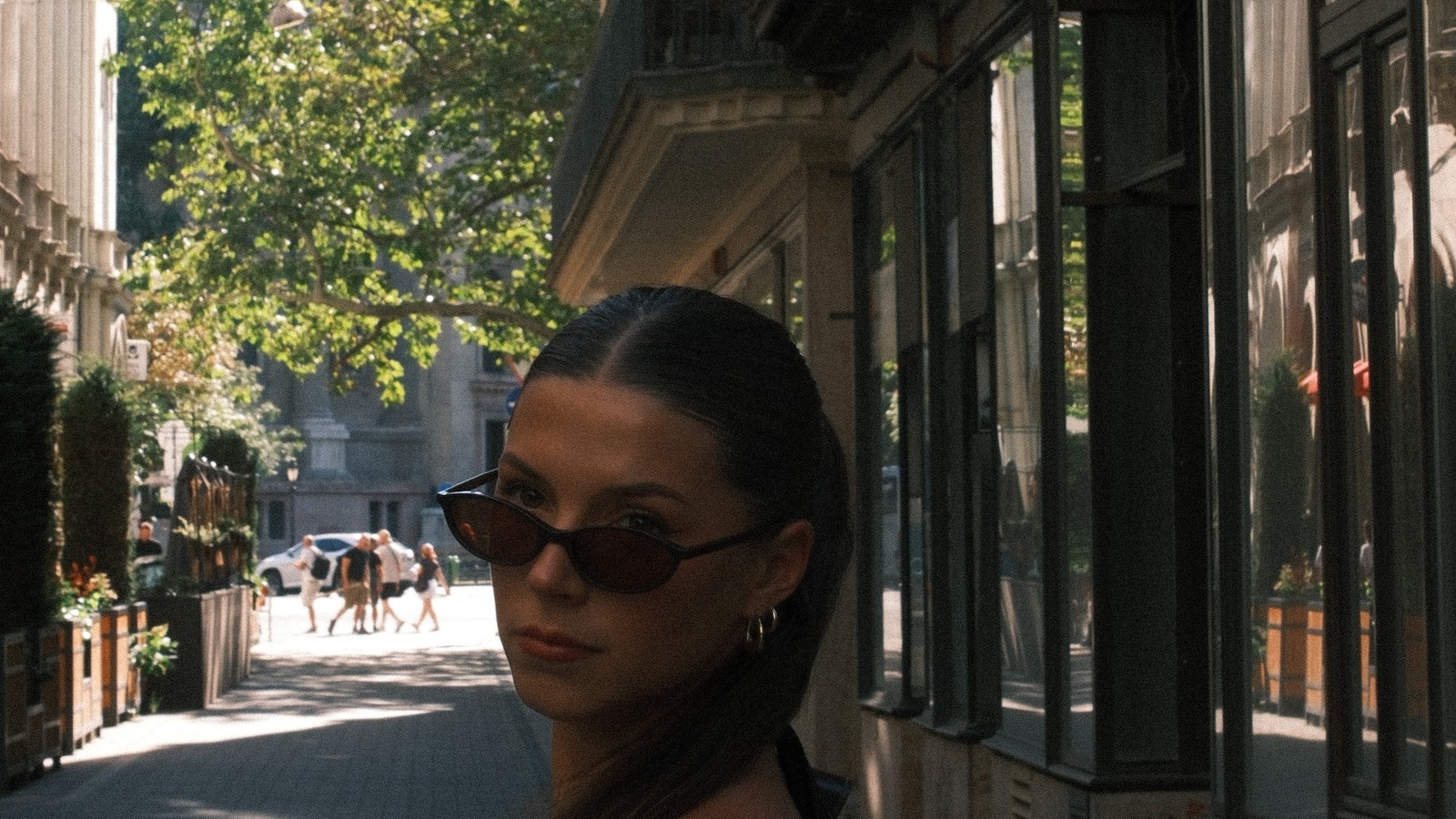 Woman in sunglasses on a sunlit Budapest street with St Stephen's Basilica behind