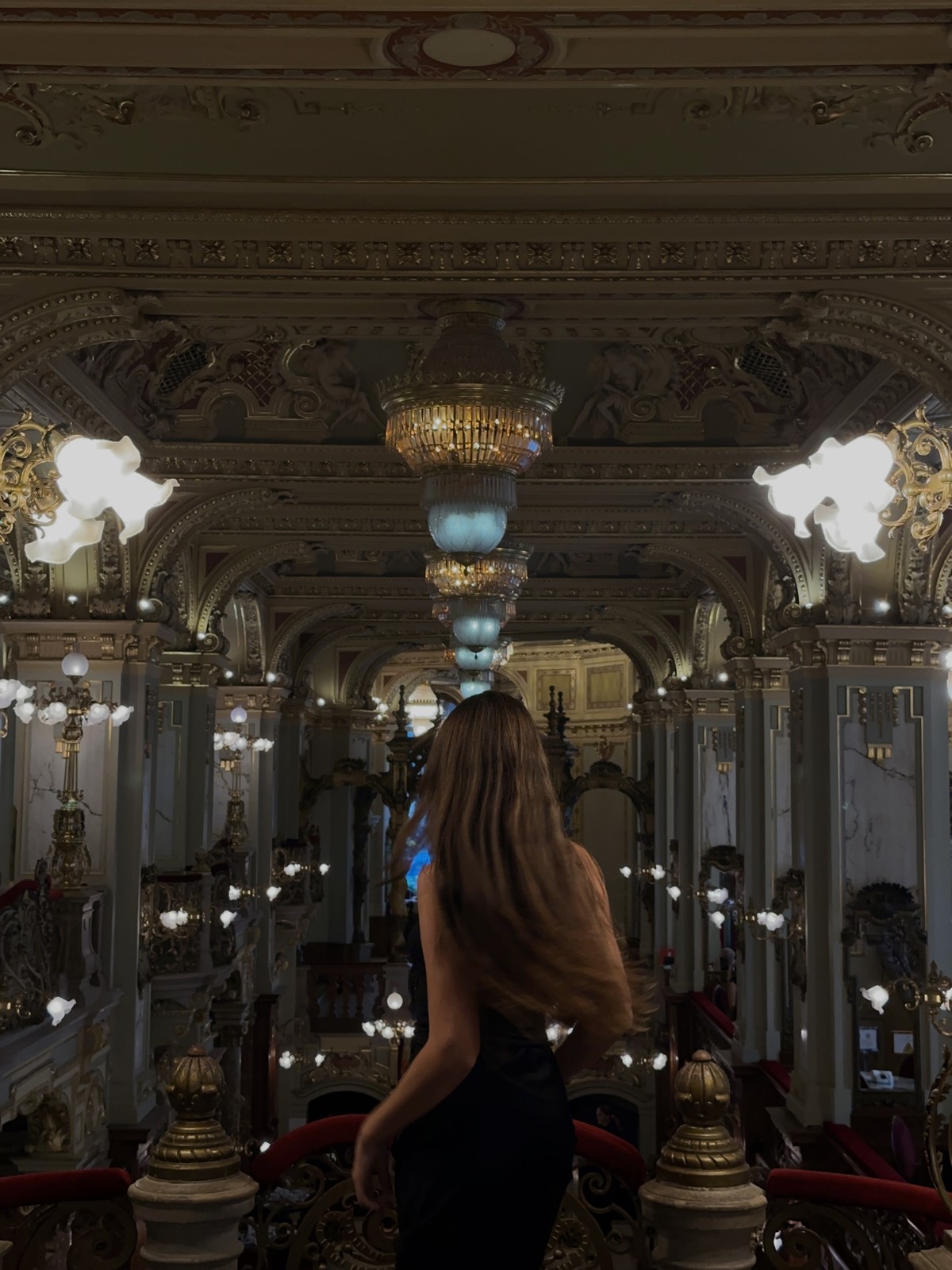Ellen standing inside an ornate Budapest café beneath chandeliers and decorated ceilings