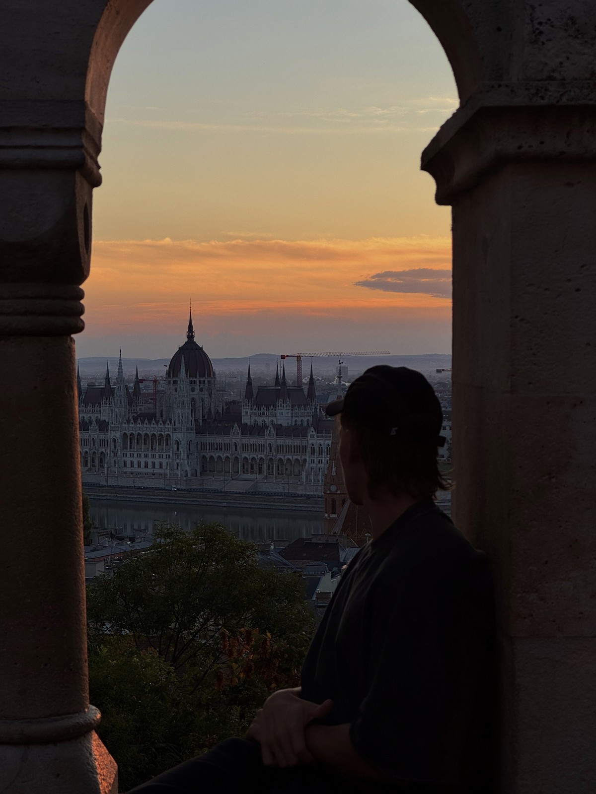 Dan looking across the river towards the Hungarian Parliament through a stone arch
