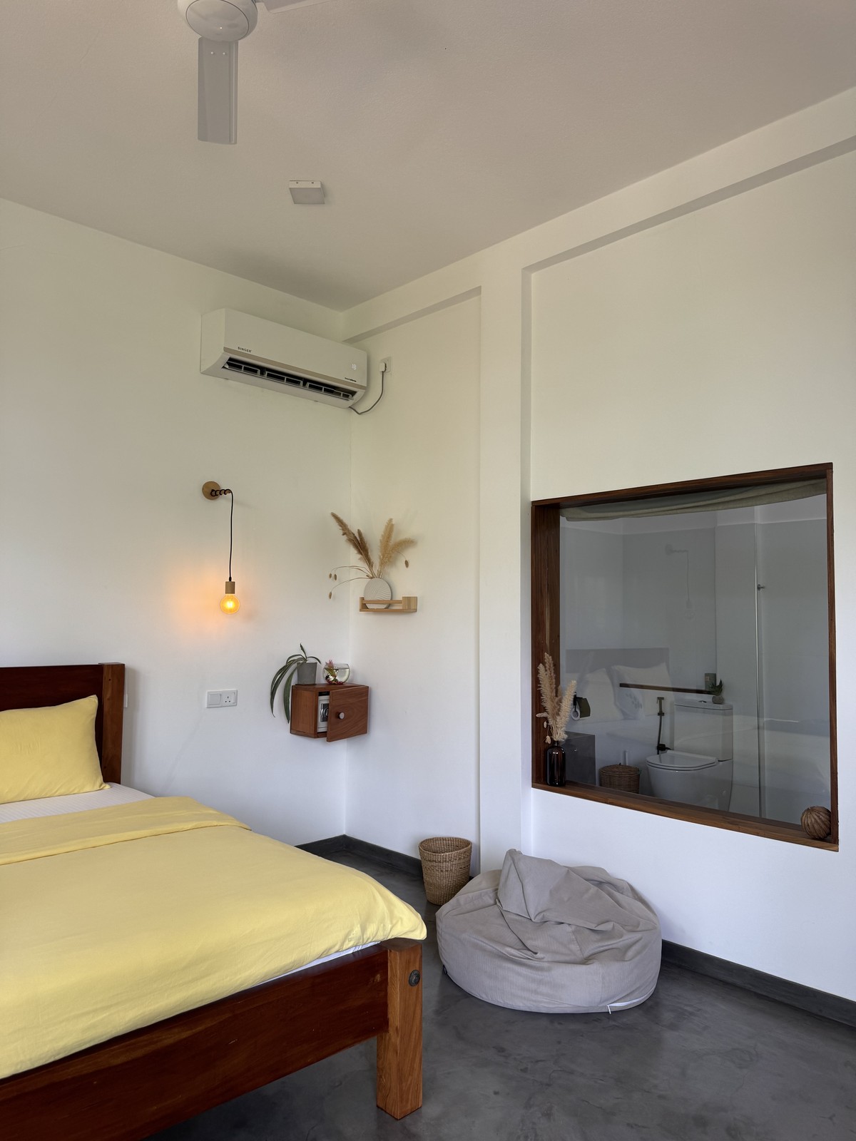 Our Hikkaduwa accommodation with yellow bedding, a ceiling fan and a glass bathroom partition