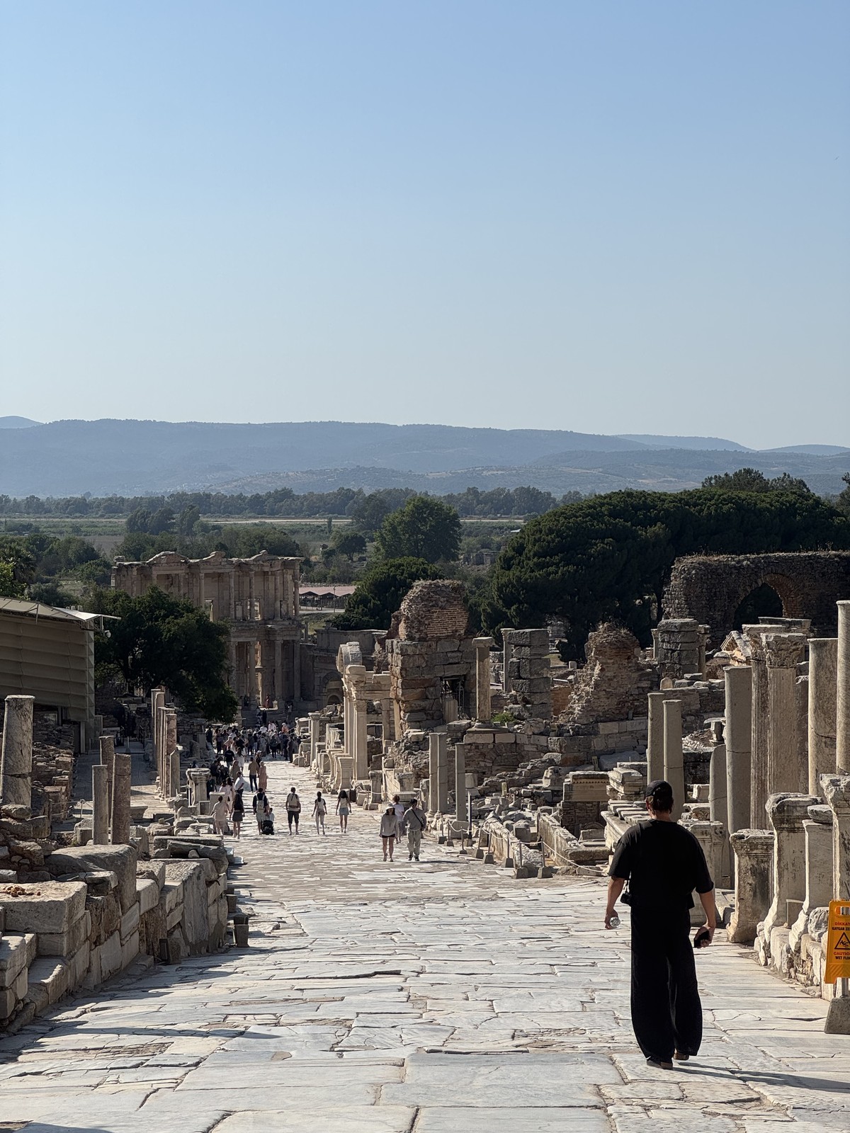 Walking down a stone street between ancient columns and ruins at Ephesus in Türkiye