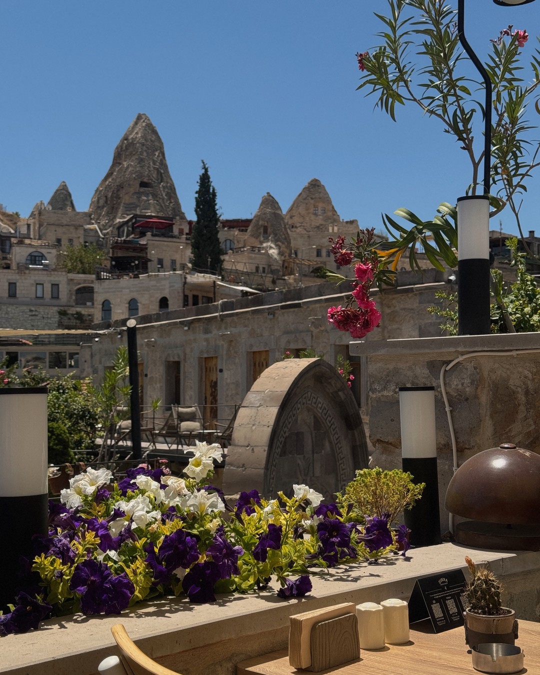 Fairy chimneys and cave houses seen over a flower-filled terrace in Cappadocia