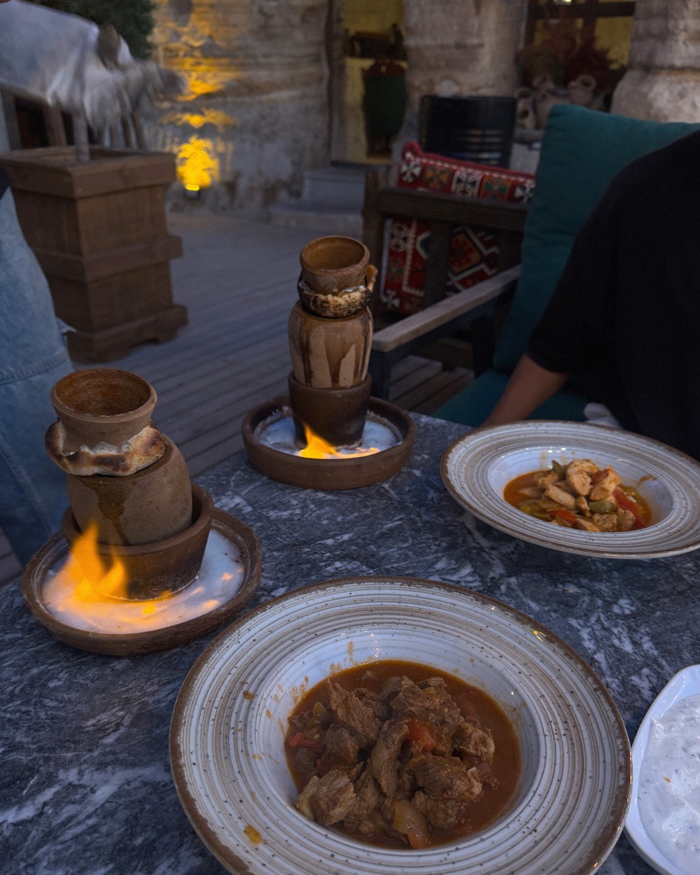 Clay pot testi kebab being flambéed and broken open at a table in a Cappadocia restaurant