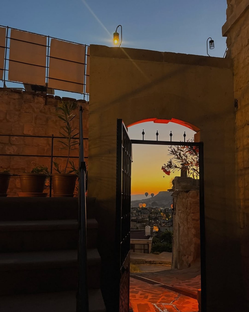 Doorway of a cave hotel room looking out to a Cappadocia sunset with a balloon in the distance