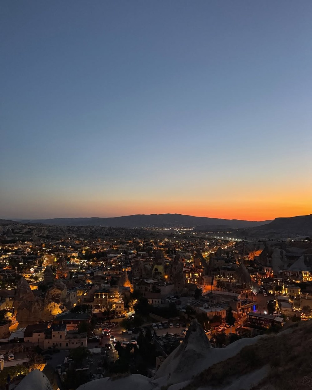 Lights of Göreme town at dusk below the rock formations of Cappadocia