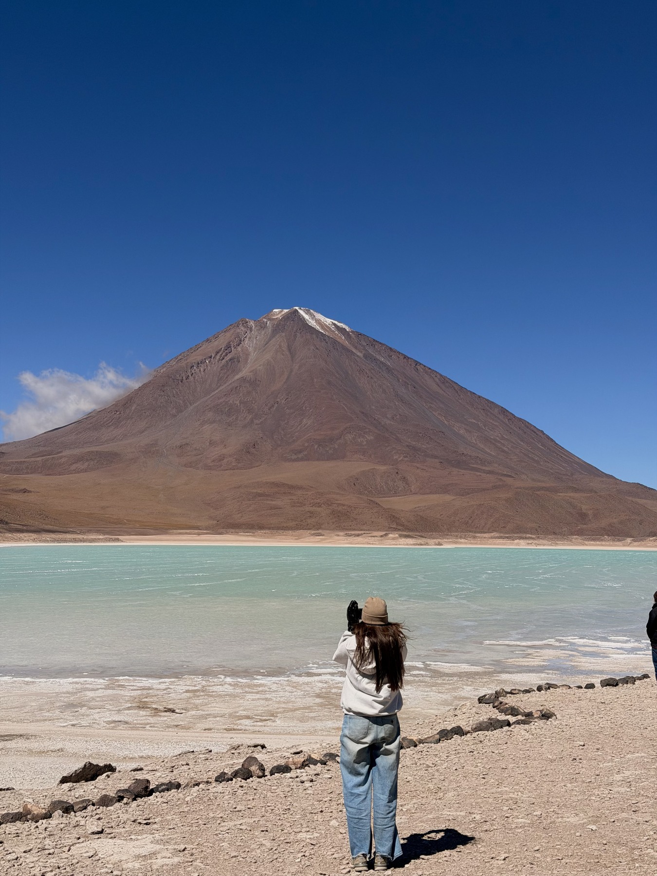 Ellen photographing a turquoise lagoon and volcano on our Bolivia crossing