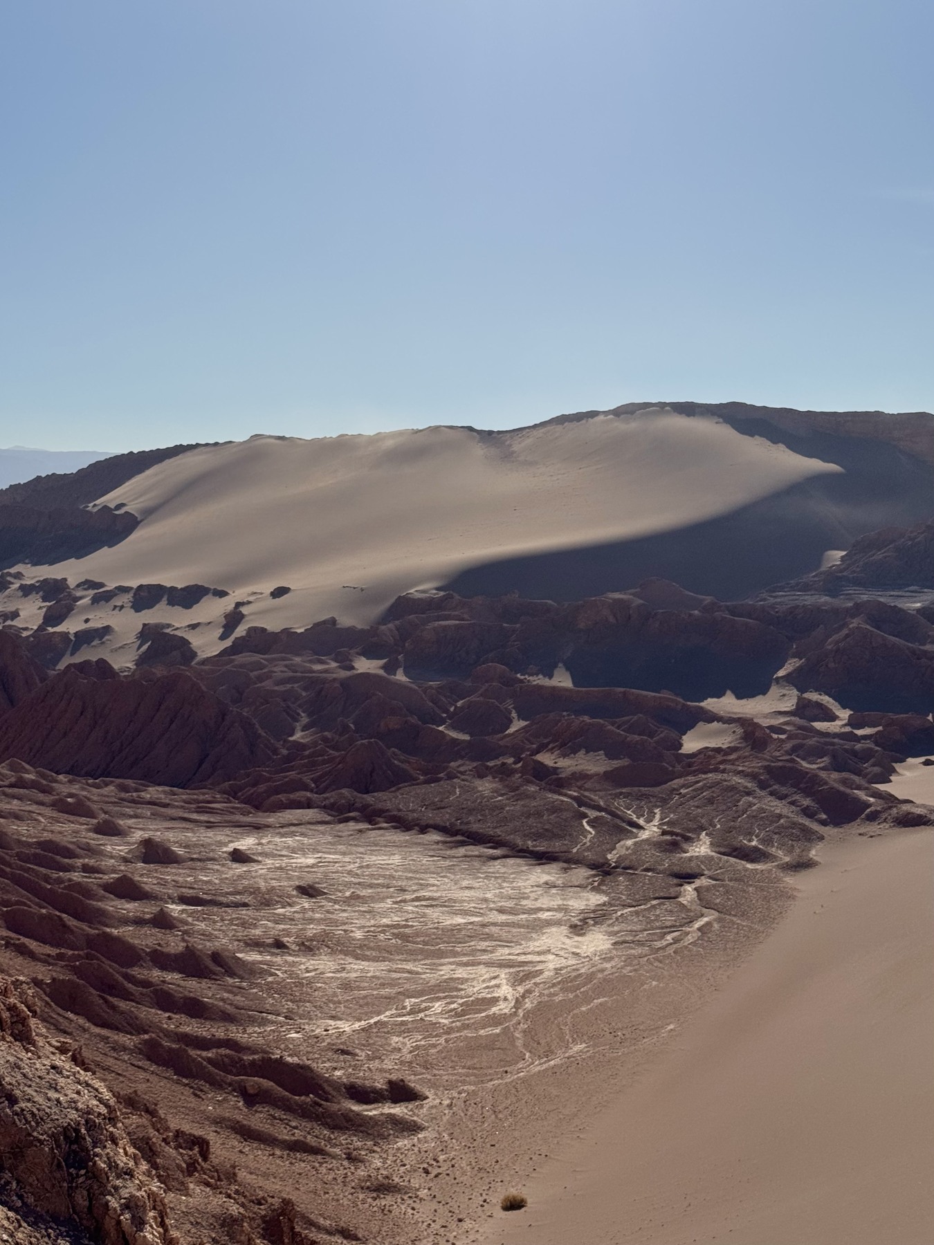 A dune above layered rock formations in Valle de la Luna