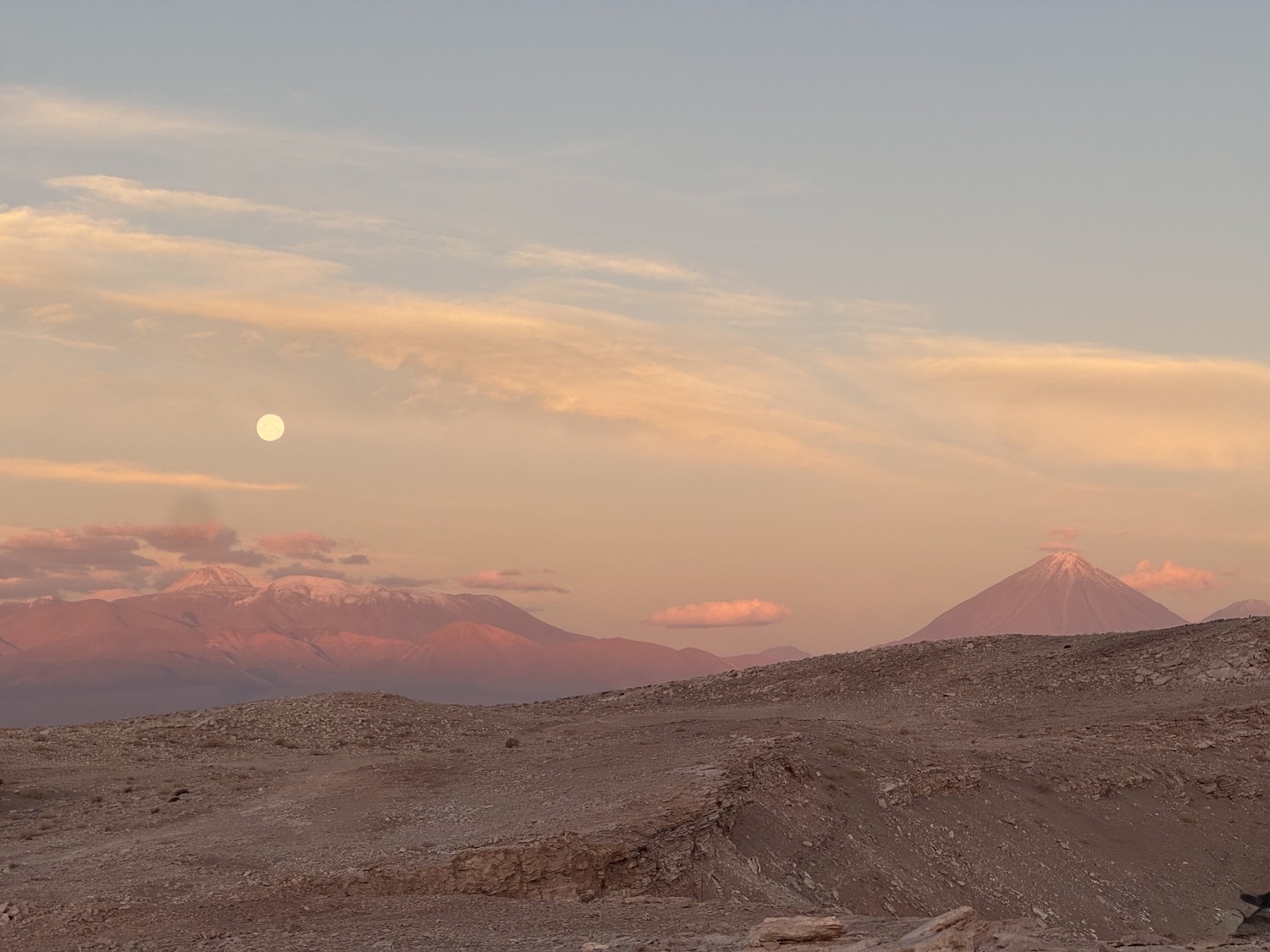 The moon rising over pink mountains in the Atacama Desert