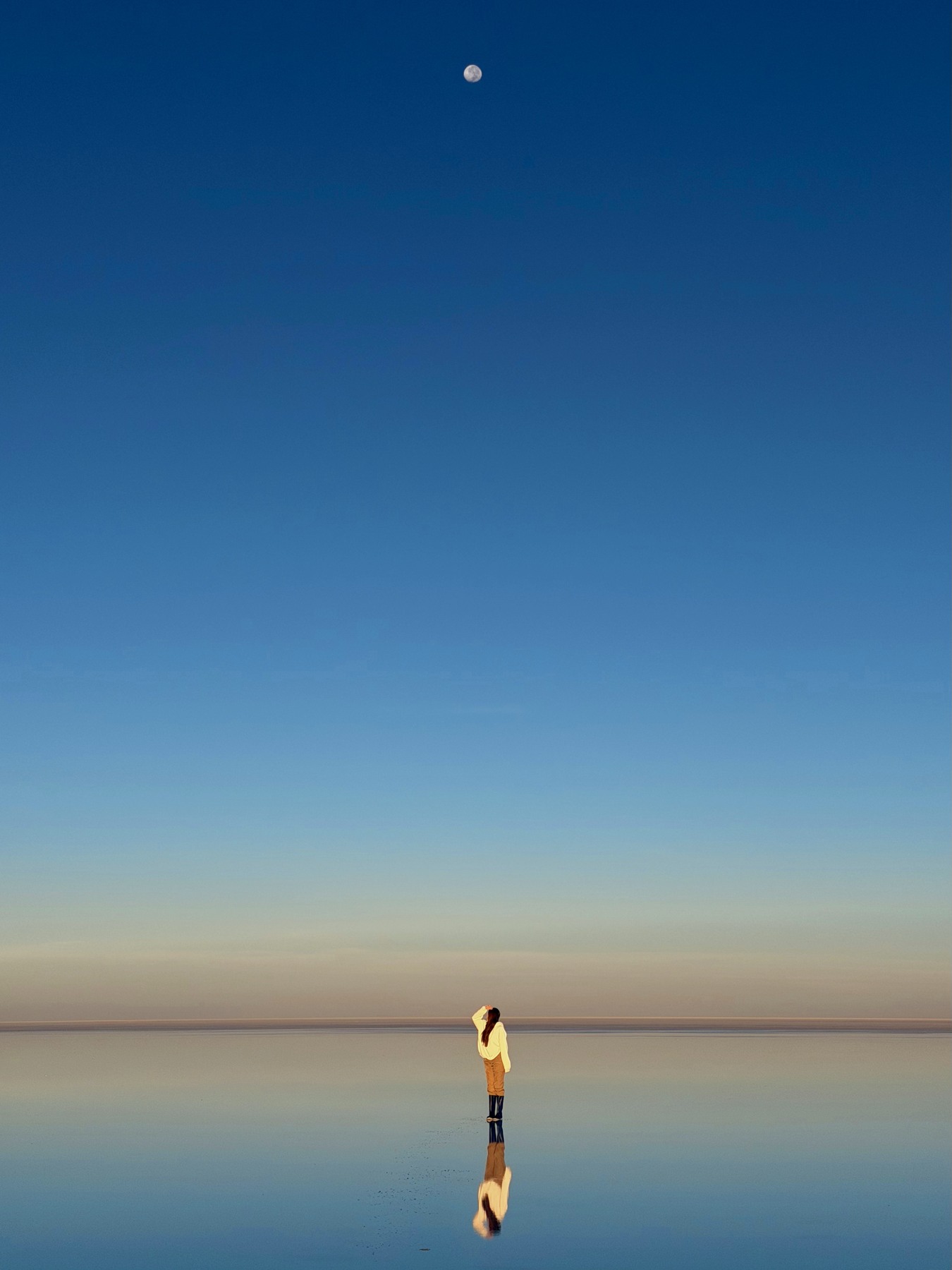 Ellen reflected beneath the moon at sunrise on the Uyuni salt flats