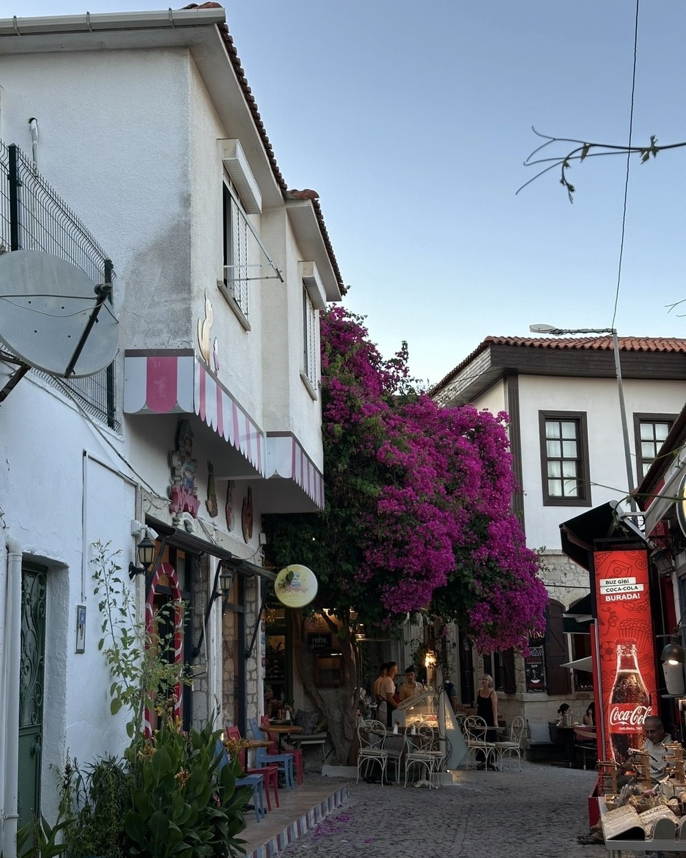 Restaurant tables under bougainvillea on a narrow street in Alaçatı