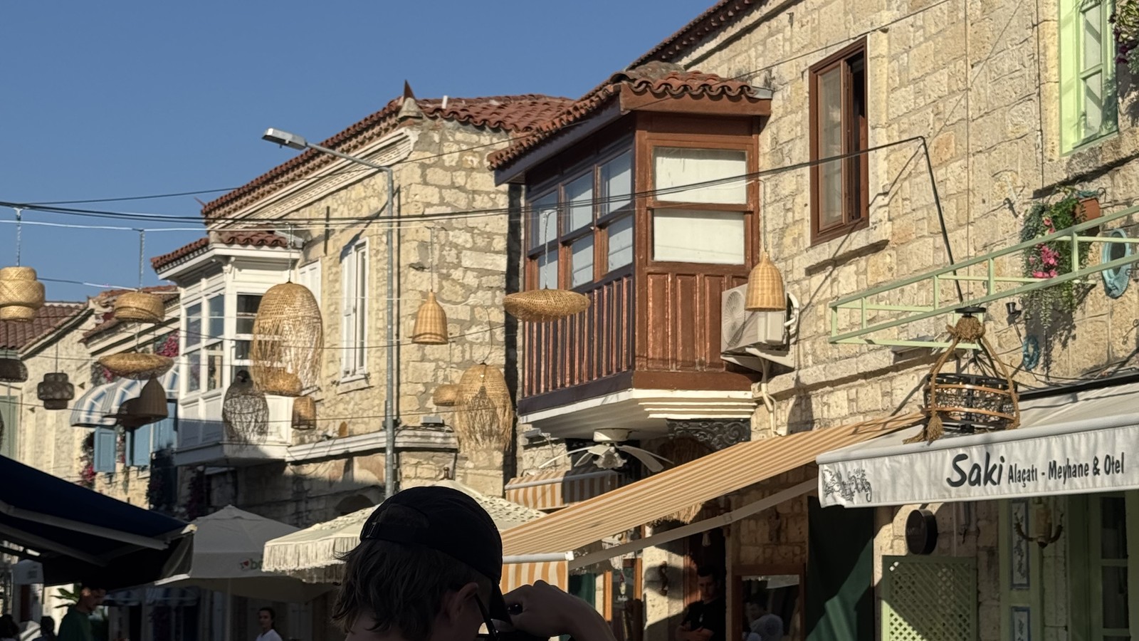Cobbled street with restaurants and bougainvillea in Alaçatı, Türkiye