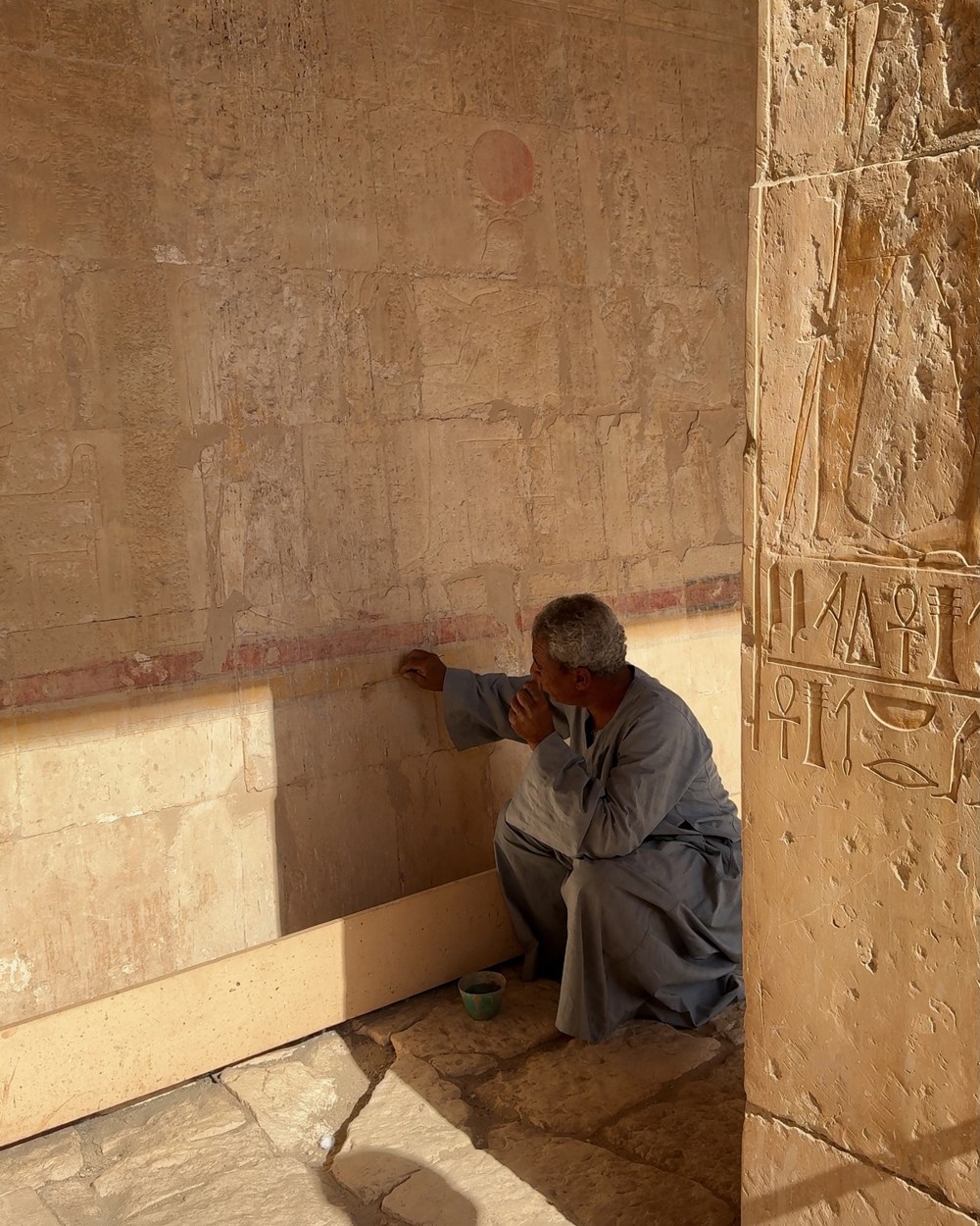 A guide explaining surviving colour and carved scenes inside the Temple of Hatshepsut in Luxor