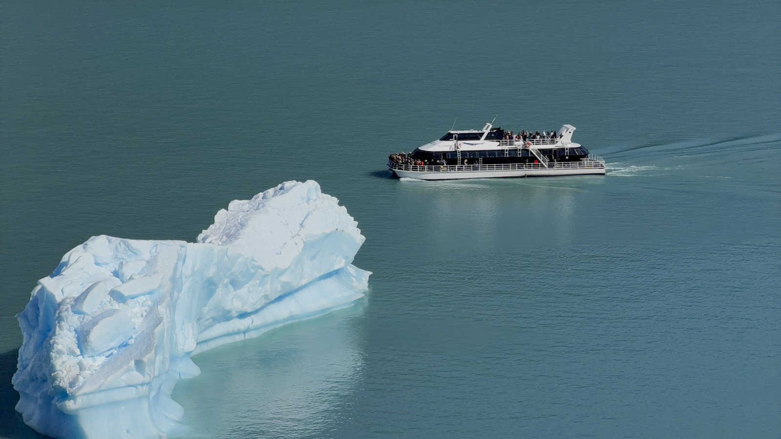A tour boat passing an iceberg on the lake in front of Perito Moreno Glacier