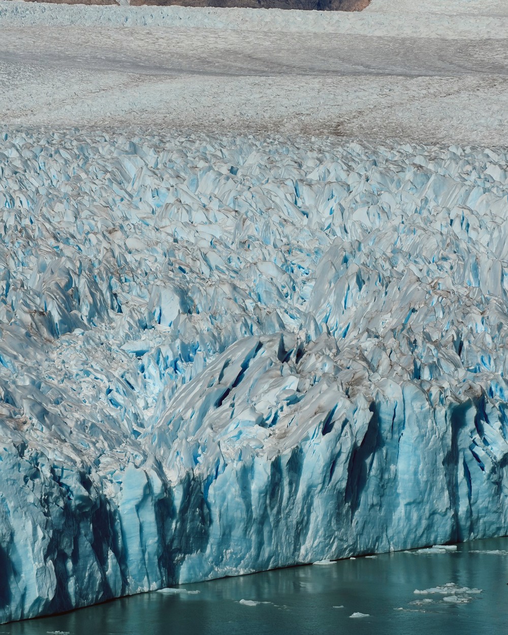 Close view of the crevasses across the top of Perito Moreno Glacier, running down to a sheer blue face over the water