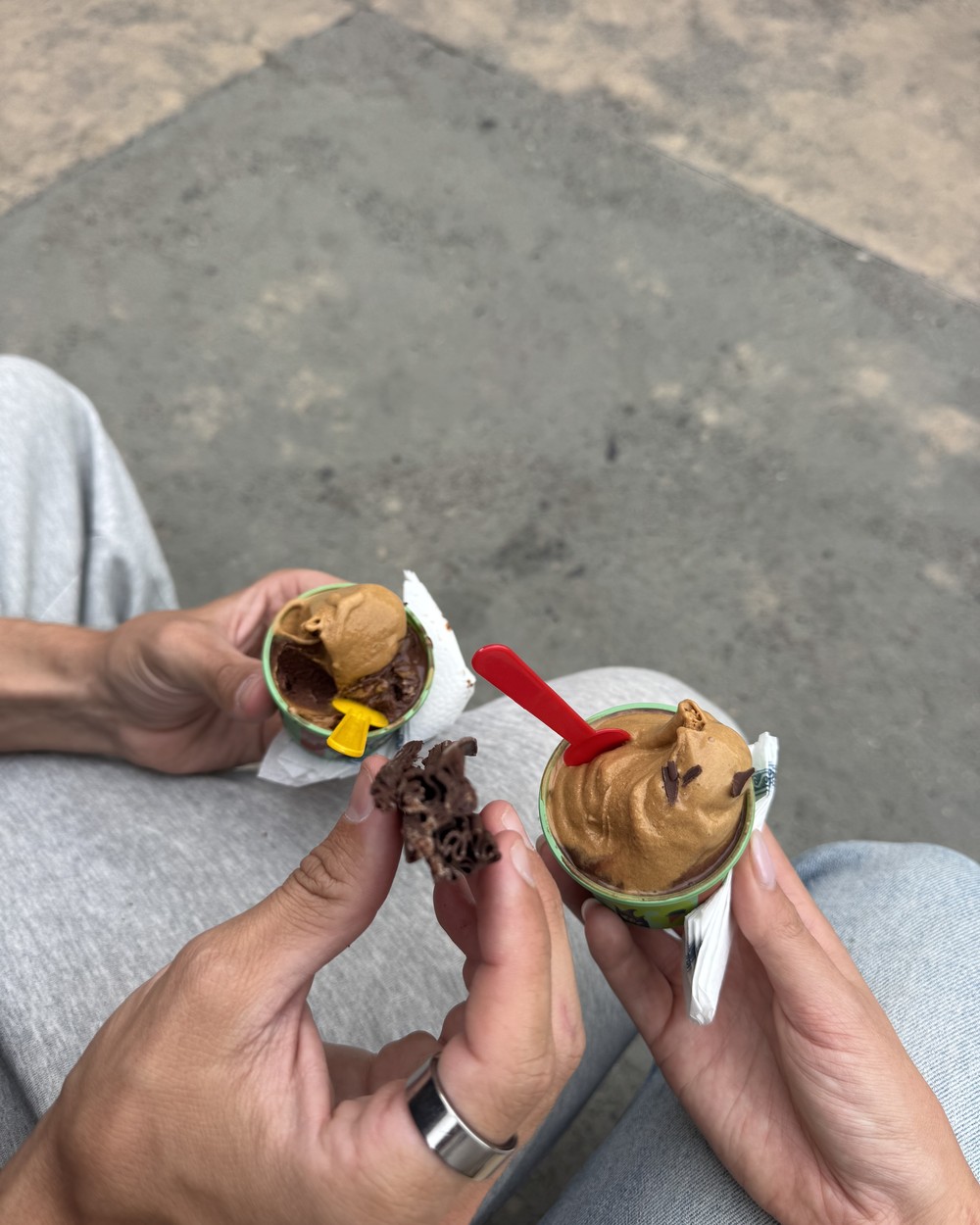 Two small cups of dulce de leche and chocolate ice cream in our hands, with a piece of chocolate flake