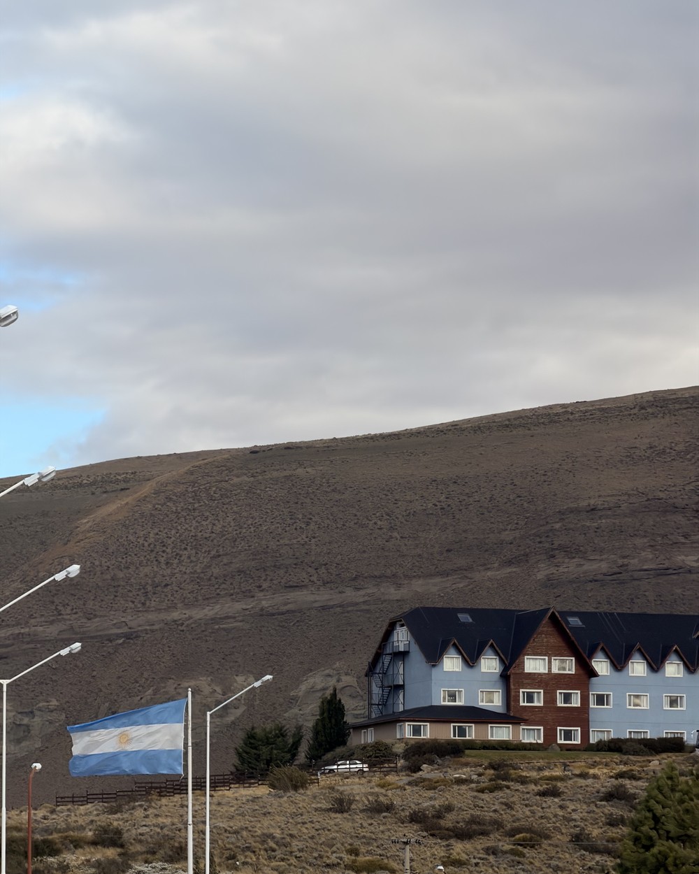 The Argentine flag flying below a large hotel on the dry hillside above El Calafate