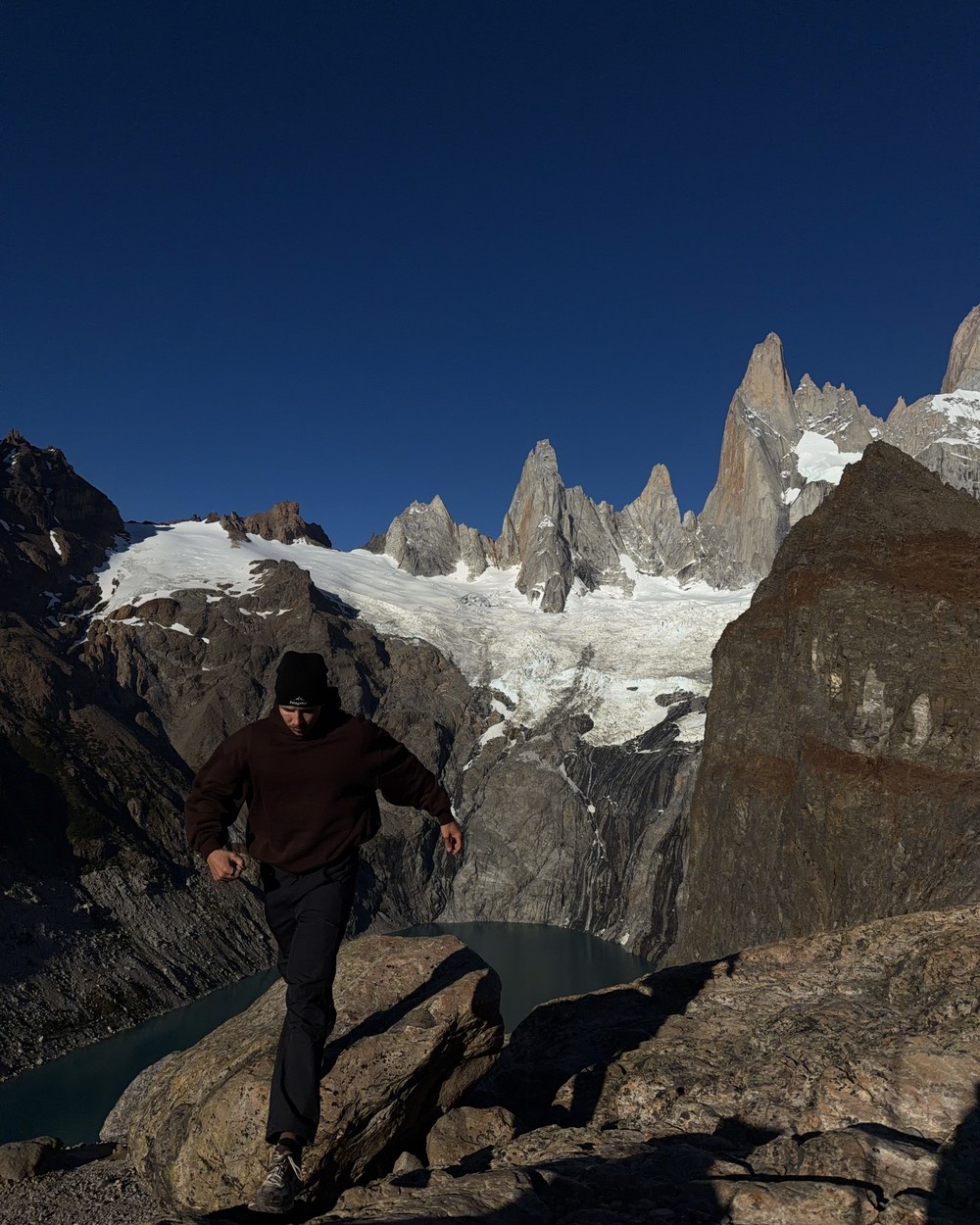 Daniel jumping between boulders with Fitz Roy behind him