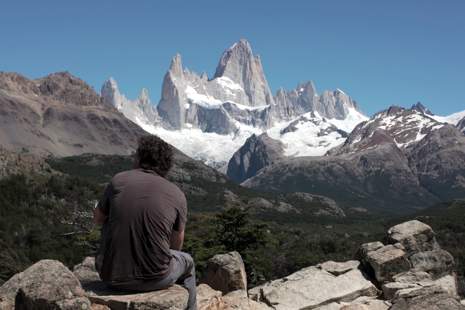 Daniel resting on a rock on the way down, looking back at Fitz Roy