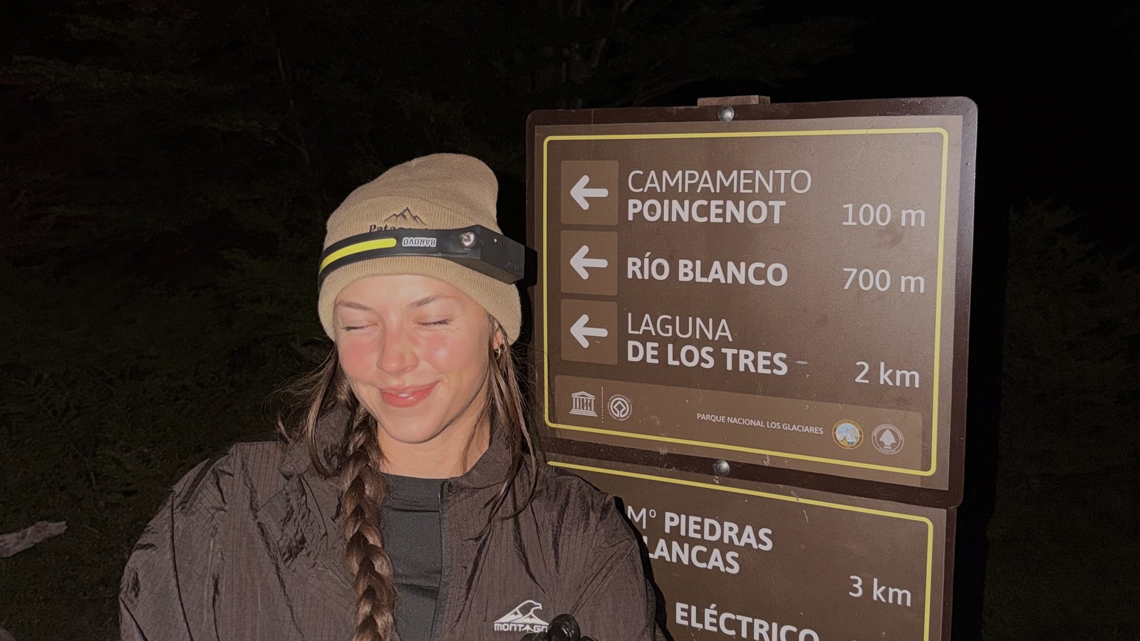Ellen in a beanie and head torch at the trail sign 2 km from Laguna de los Tres