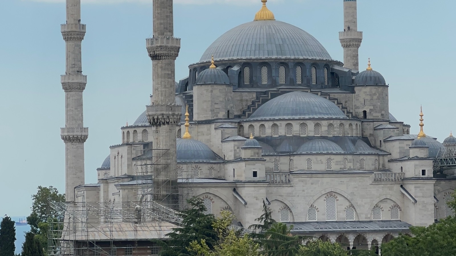 Woman at a rooftop restaurant table with the domes and minarets of the Blue Mosque behind in Istanbul