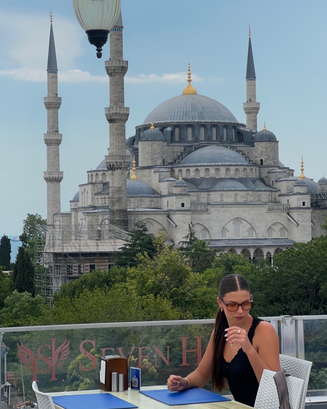 Woman at a rooftop restaurant table with the Blue Mosque behind in Istanbul