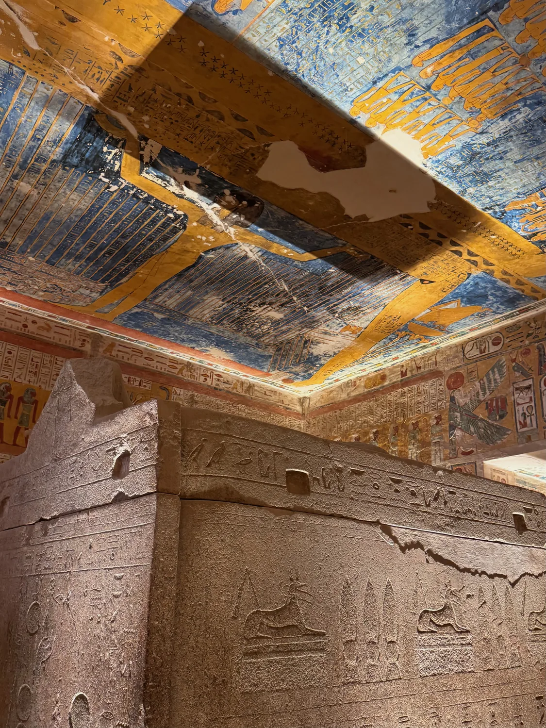 Blue, gold and ochre paintings covering the ceiling inside a tomb in the Valley of the Kings in Luxor