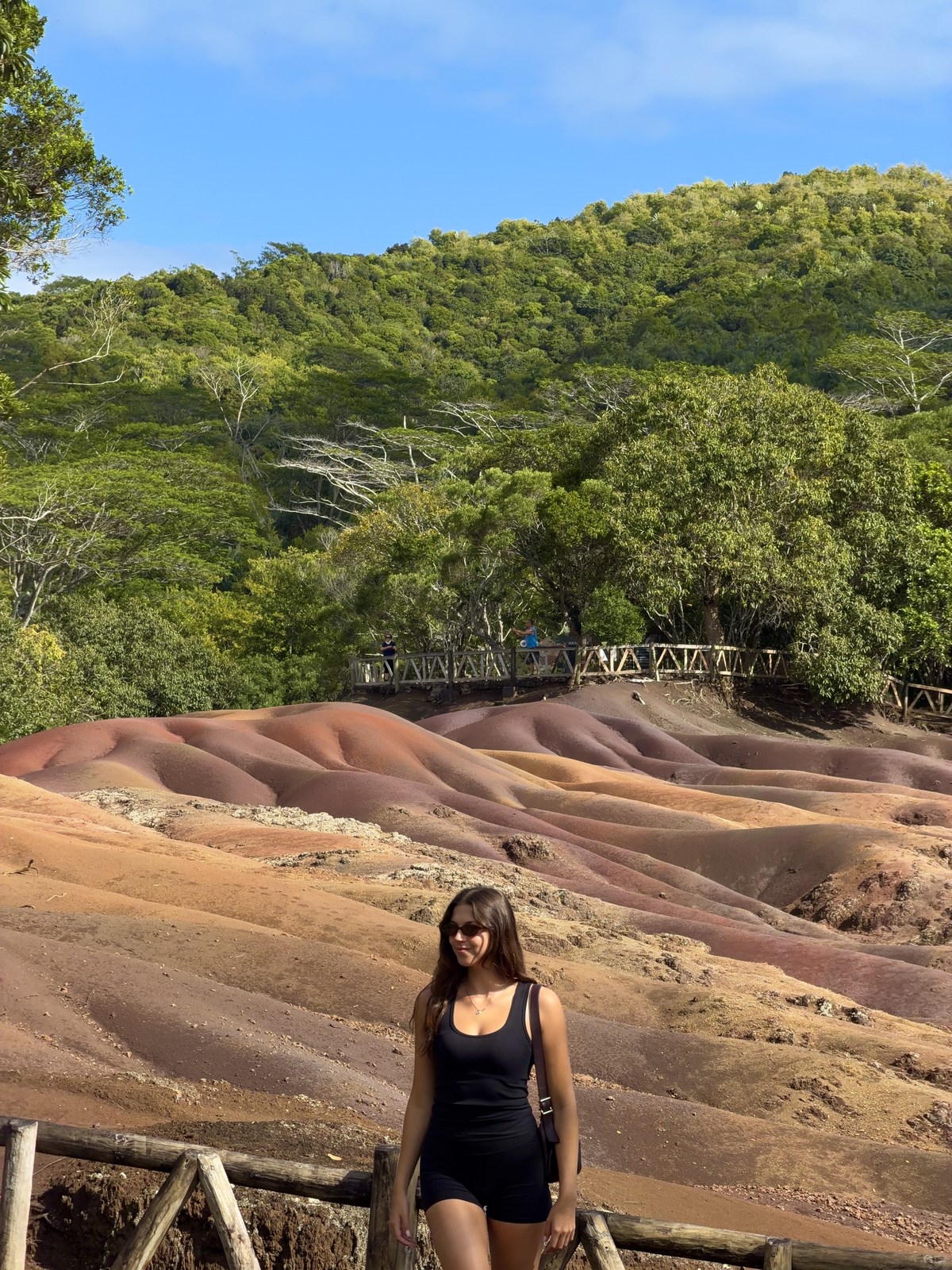 Ellen standing on a viewing path beside coloured earth and green hills in Mauritius