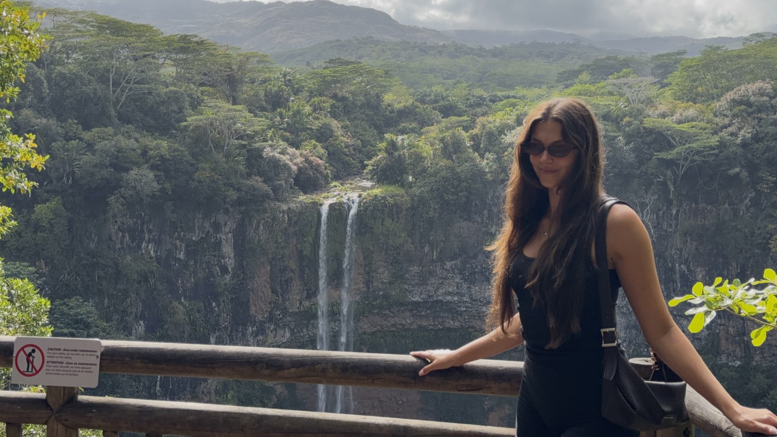 Ellen at a viewpoint overlooking a waterfall and green hills in Mauritius
