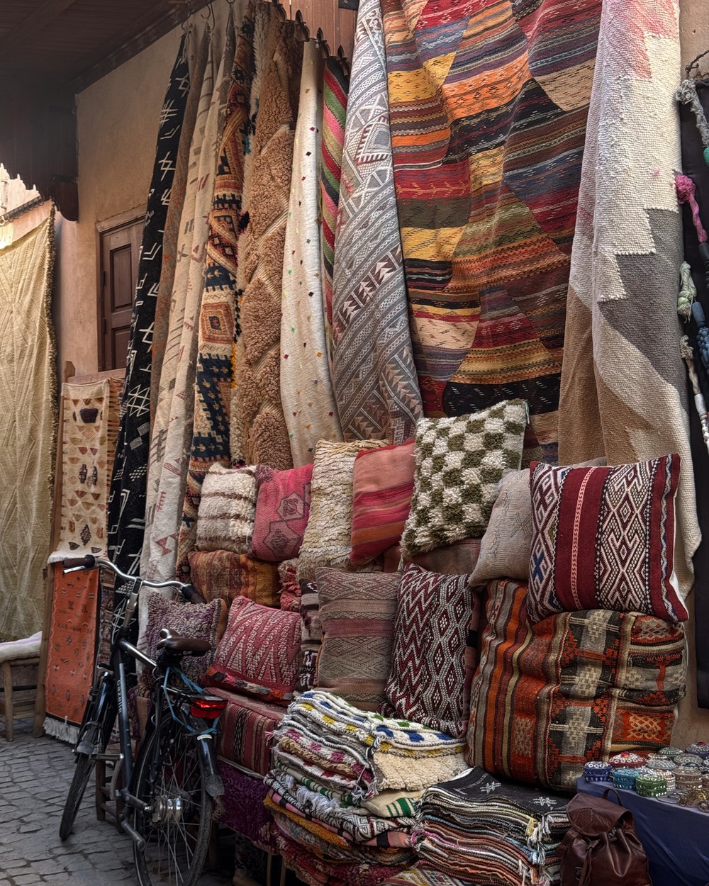 Stacks of colourful Berber rugs and cushions outside a shop in the Marrakech medina, Morocco