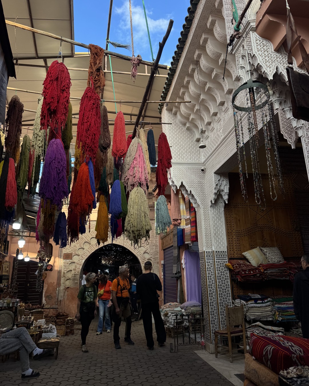 Brightly coloured wool tassels hanging above a busy lane in the Marrakech souks, Morocco