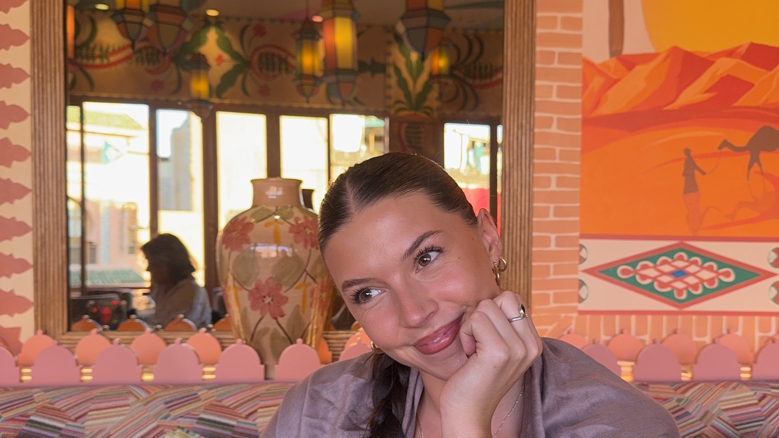 Ellen sitting in a brightly painted cafe with lanterns and patterned cushions in Marrakech, Morocco