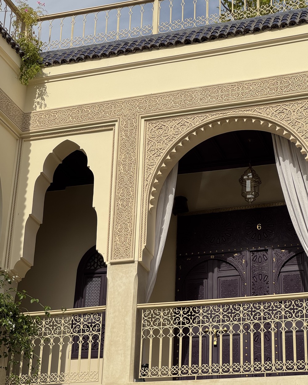 Arched riad gallery with carved plasterwork and a wrought iron balcony in Marrakech, Morocco