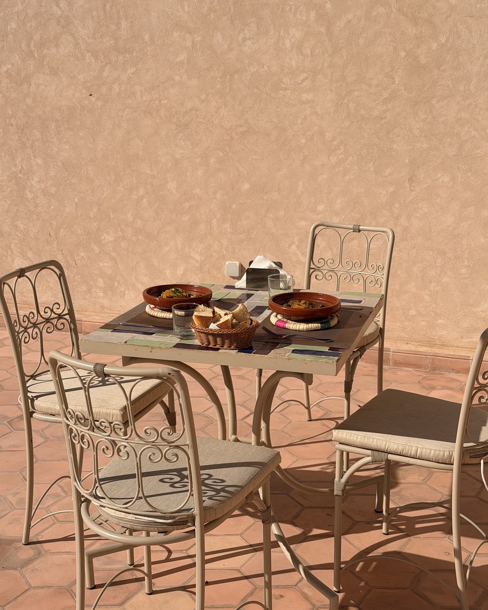 Breakfast laid out with tagine dishes and coffee on a riad roof terrace in Marrakech, Morocco