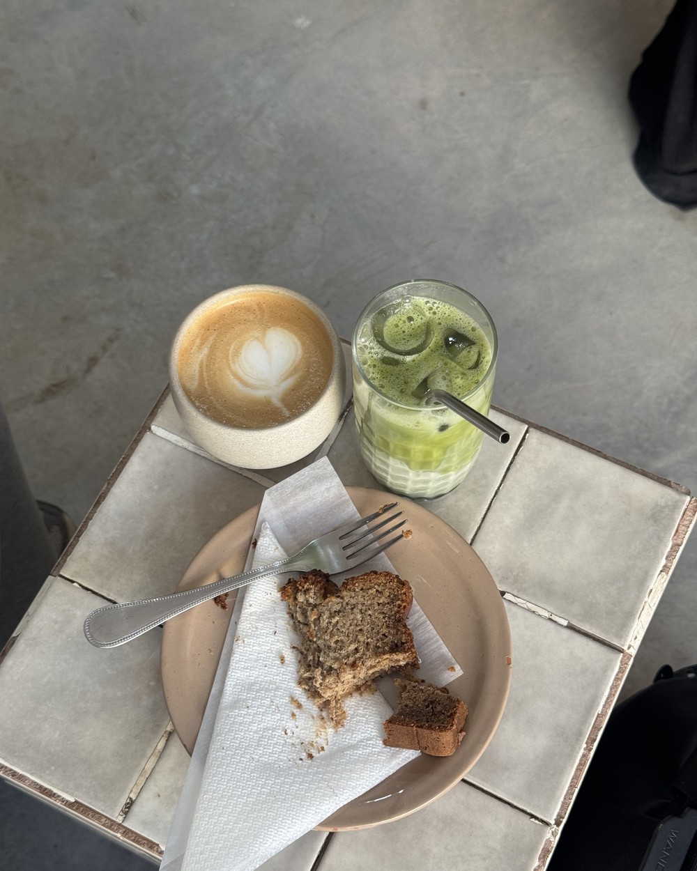 Coffee, matcha and a slice of banana bread on a tiled table in Tamraght, Morocco