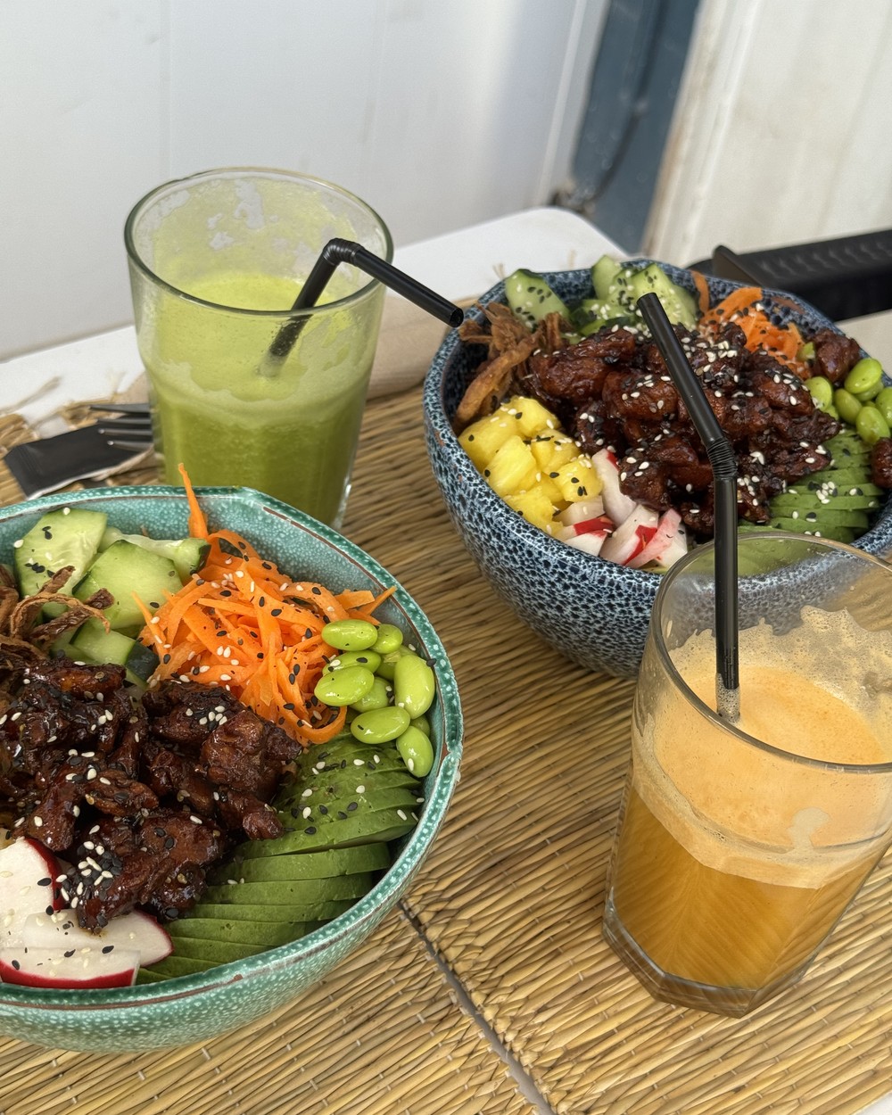 Poke bowl with fresh juices on a wooden table at Ohana Poke and Vitamin Bar in Tamraght, Morocco